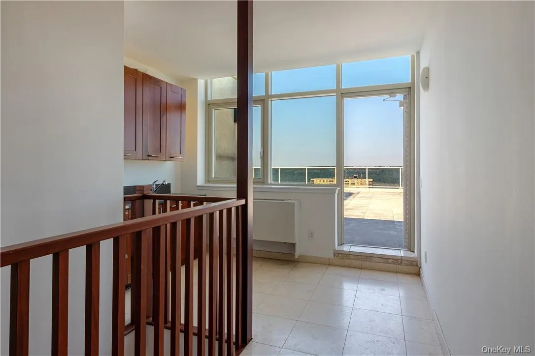 Hallway featuring light tile patterned flooring and a wealth of natural light Hallway featuring light tile patterned flooring and a wealth of natural light
