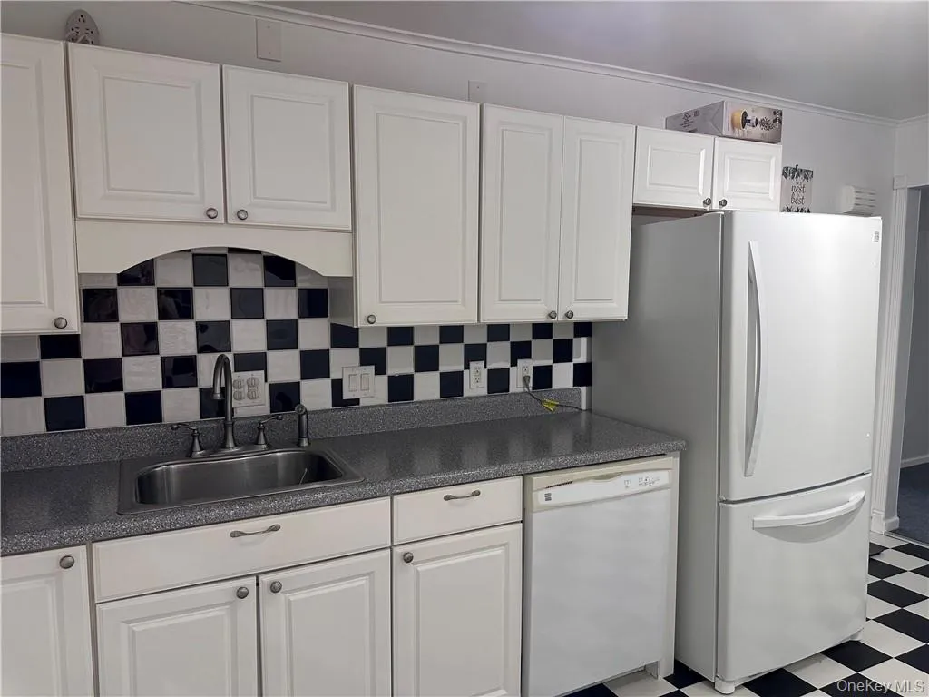 Kitchen featuring white cabinets, sink, white appliances, and light tile patterned floors Kitchen featuring white cabinets, sink, white appliances, and light tile patterned floors