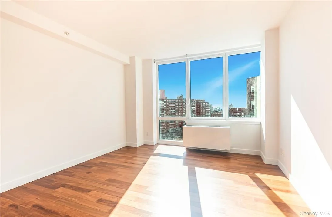 Empty room featuring light hardwood / wood-style floors, radiator, and plenty of natural light Empty room featuring light hardwood / wood-style floors, radiator, and plenty of natural light