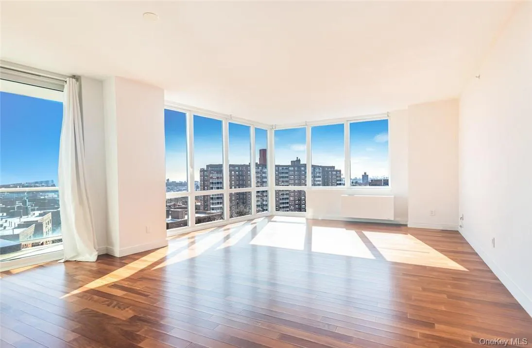 Unfurnished room featuring radiator heating unit, floor to ceiling windows, and hardwood / wood-style floors Unfurnished room featuring radiator heating unit, floor to ceiling windows, and hardwood / wood-style floors