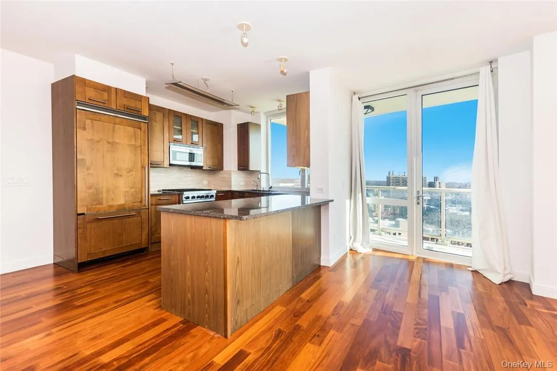 Kitchen with tasteful backsplash, sink, dark hardwood / wood-style floors, paneled refrigerator, and kitchen peninsula Kitchen with tasteful backsplash, sink, dark hardwood / wood-style floors, paneled refrigerator, and kitchen peninsula