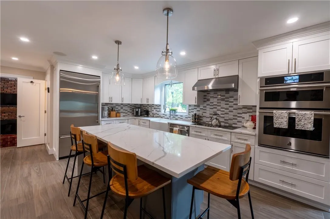 Kitchen with stainless steel appliances, white cabinets, hanging light fixtures, and a kitchen island Kitchen with stainless steel appliances, white cabinets, hanging light fixtures, and a kitchen island