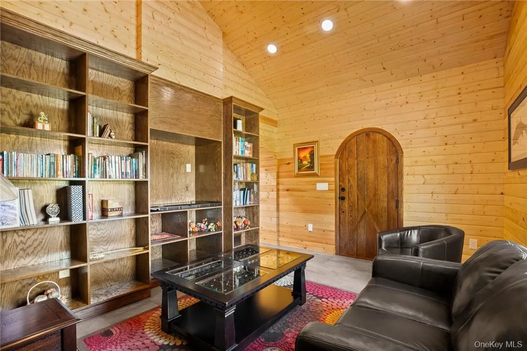 Living room with wood ceiling, built in shelves, high vaulted ceiling, and wood walls Living room with wood ceiling, built in shelves, high vaulted ceiling, and wood walls