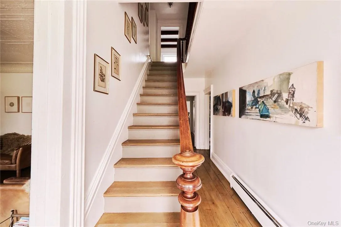 Stairs featuring wood-type flooring and a baseboard heating unit Stairs featuring wood-type flooring and a baseboard heating unit