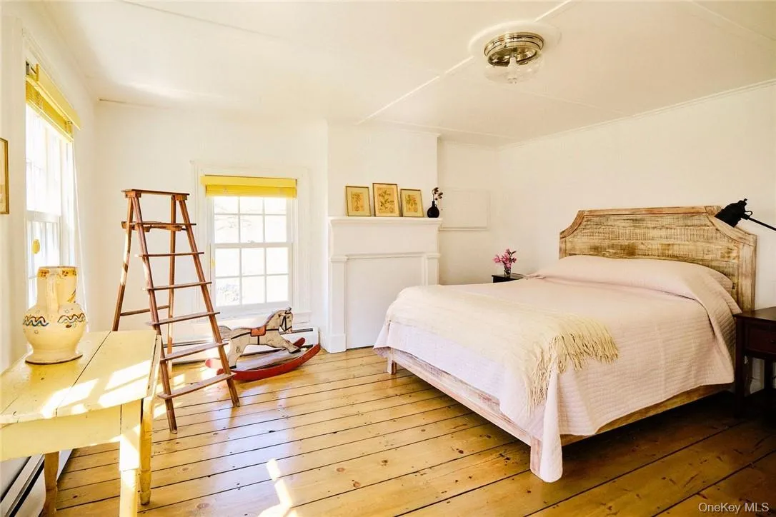 Bedroom featuring a baseboard heating unit and hardwood / wood-style flooring Bedroom featuring a baseboard heating unit and hardwood / wood-style flooring