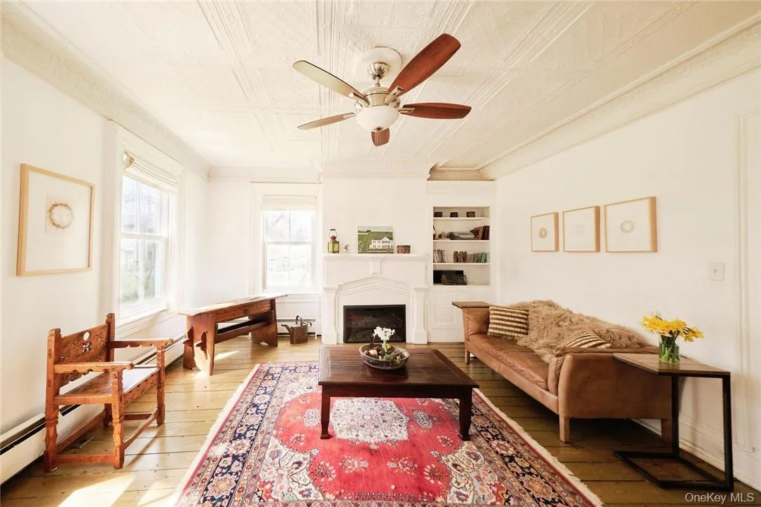 Living room with ceiling fan, built in features, and light hardwood / wood-style floors Living room with ceiling fan, built in features, and light hardwood / wood-style floors