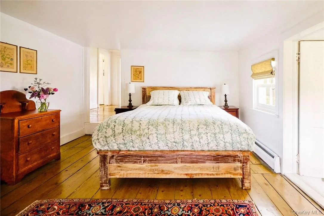 Bedroom featuring wood-type flooring and a baseboard heating unit Bedroom featuring wood-type flooring and a baseboard heating unit