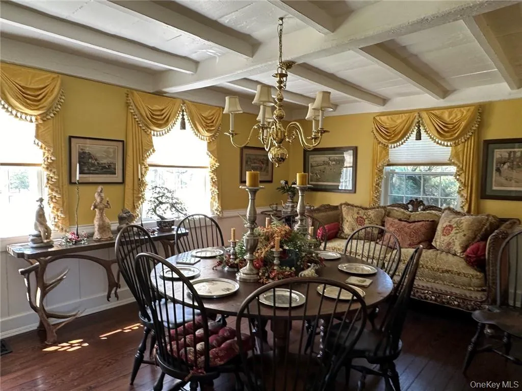 Dining room featuring beam ceiling, a notable chandelier, wood-type flooring, and a wealth of natural light Dining room featuring beam ceiling, a notable chandelier, wood-type flooring, and a wealth of natural light