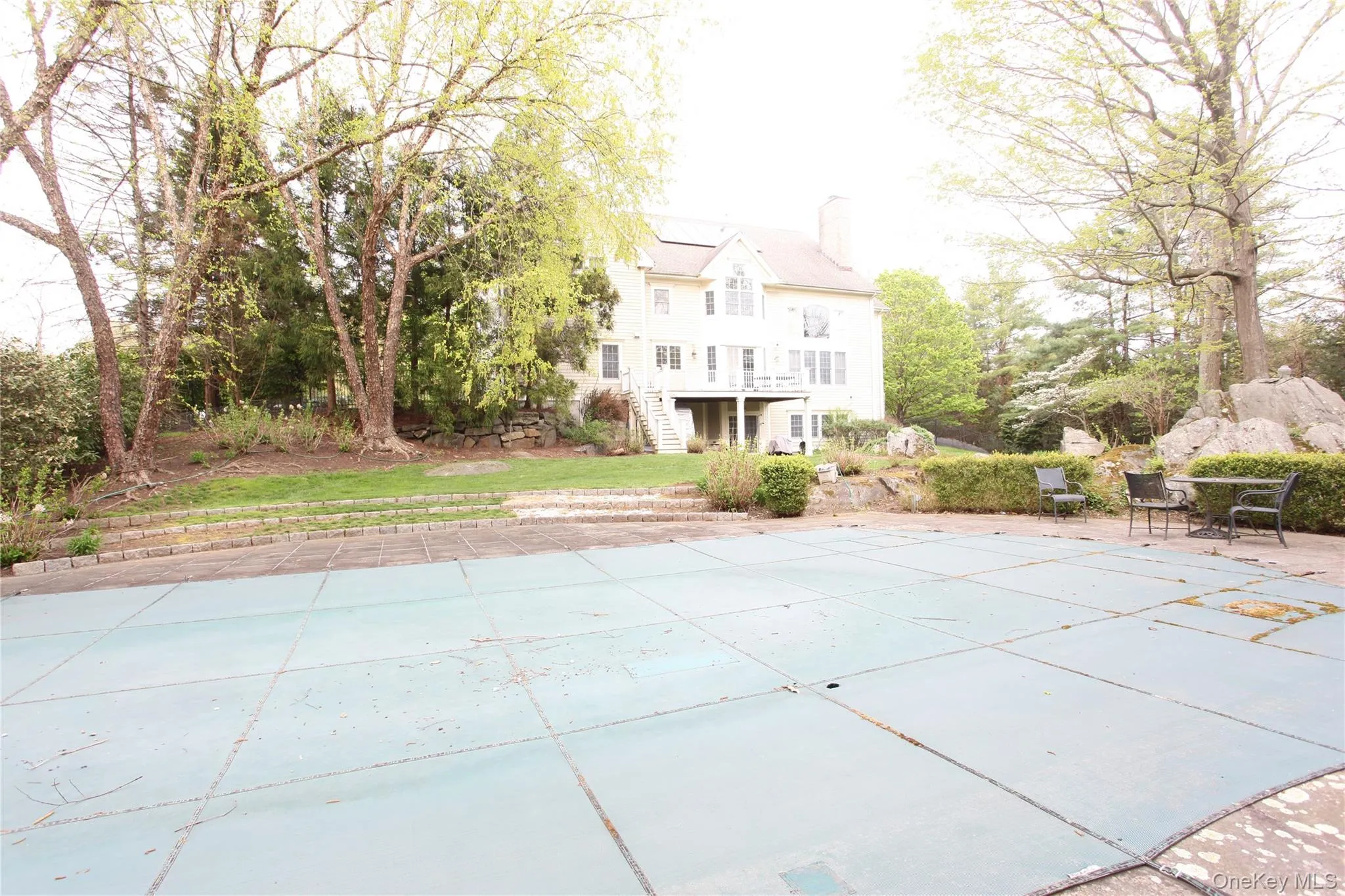 Rear exterior featuring a multi-level deck, a covered pool area, and mature trees Rear exterior featuring a multi-level deck, a covered pool area, and mature trees