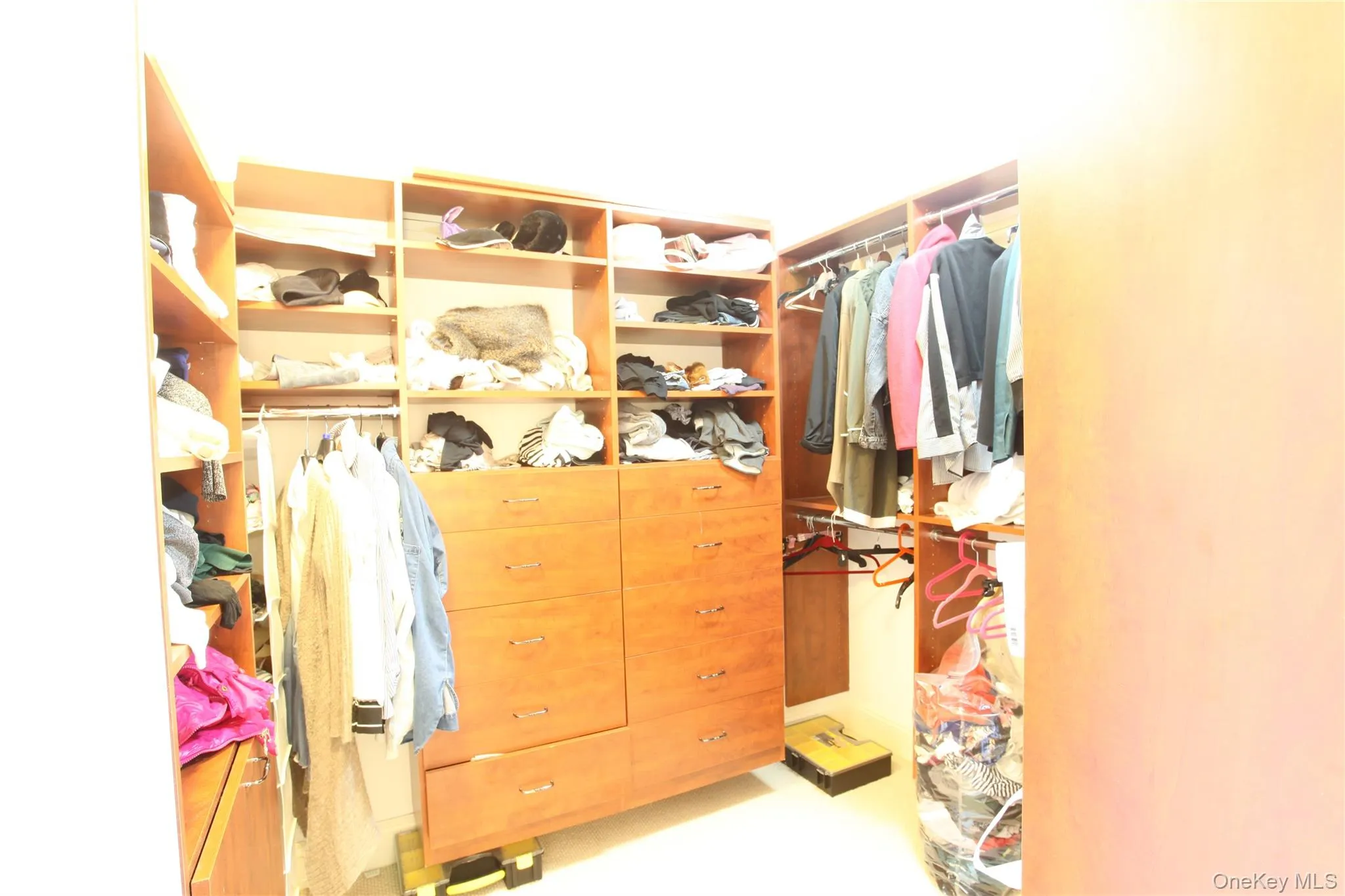 Custom wood-finish closet system featuring integrated shelving, multiple hanging rods, and built-in drawers Custom wood-finish closet system featuring integrated shelving, multiple hanging rods, and built-in drawers