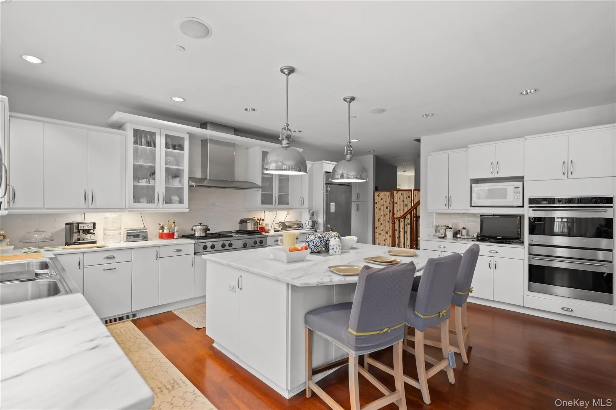 Kitchen with stainless steel appliances, a kitchen bar, white cabinets, and decorative backsplash Kitchen with stainless steel appliances, a kitchen bar, white cabinets, and decorative backsplash