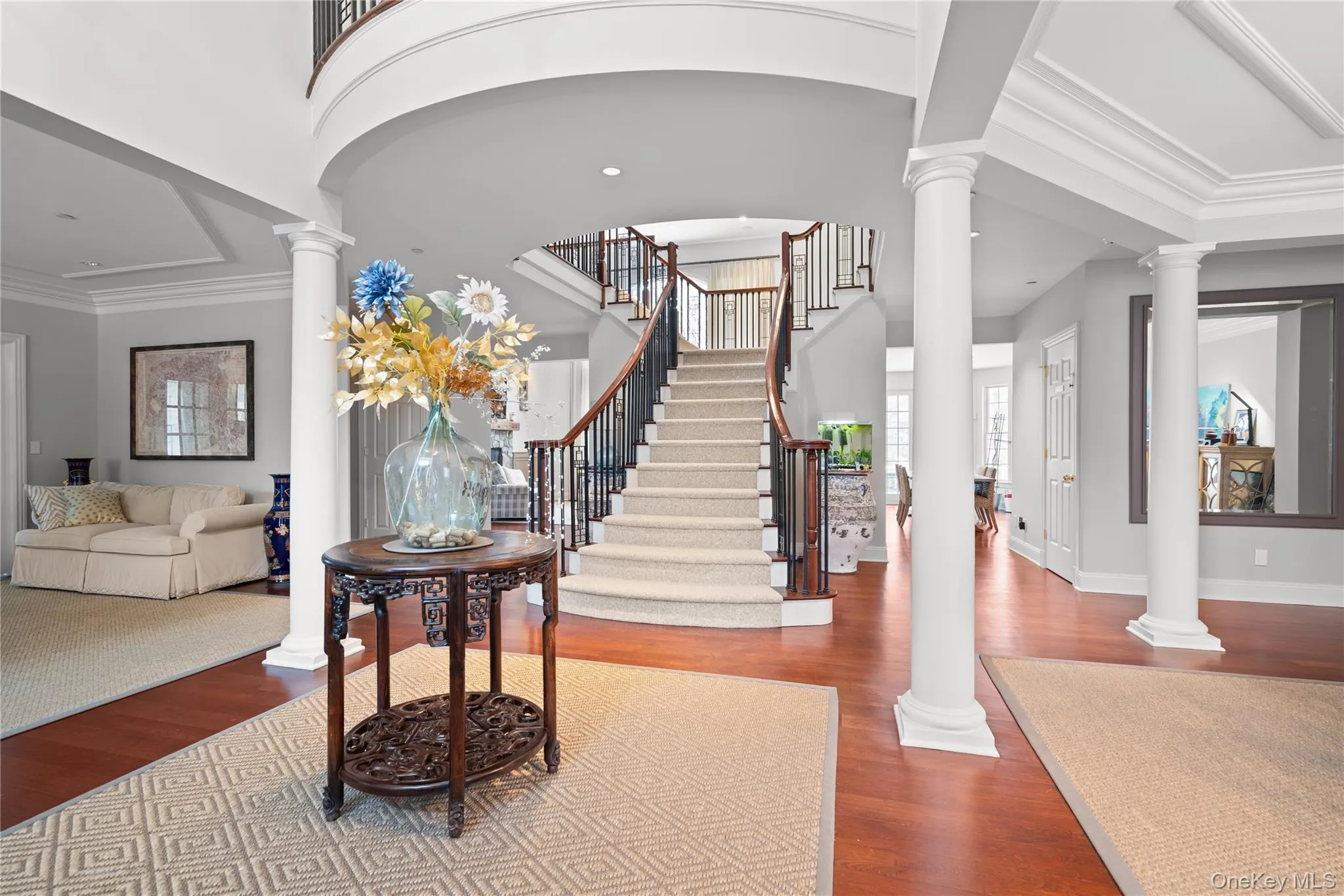 Entrance foyer with decorative columns, dark wood-style flooring, and ornamental molding Entrance foyer with decorative columns, dark wood-style flooring, and ornamental molding