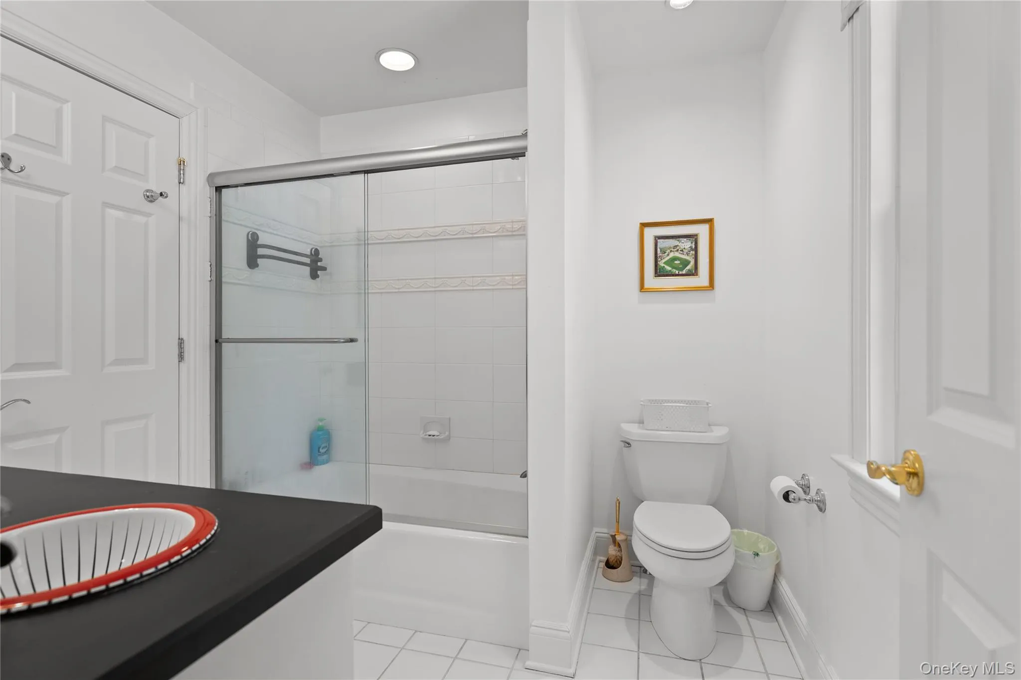 Bathroom featuring vanity, light tile patterned floors, bath / shower combo with glass door, and recessed lighting Bathroom featuring vanity, light tile patterned floors, bath / shower combo with glass door, and recessed lighting