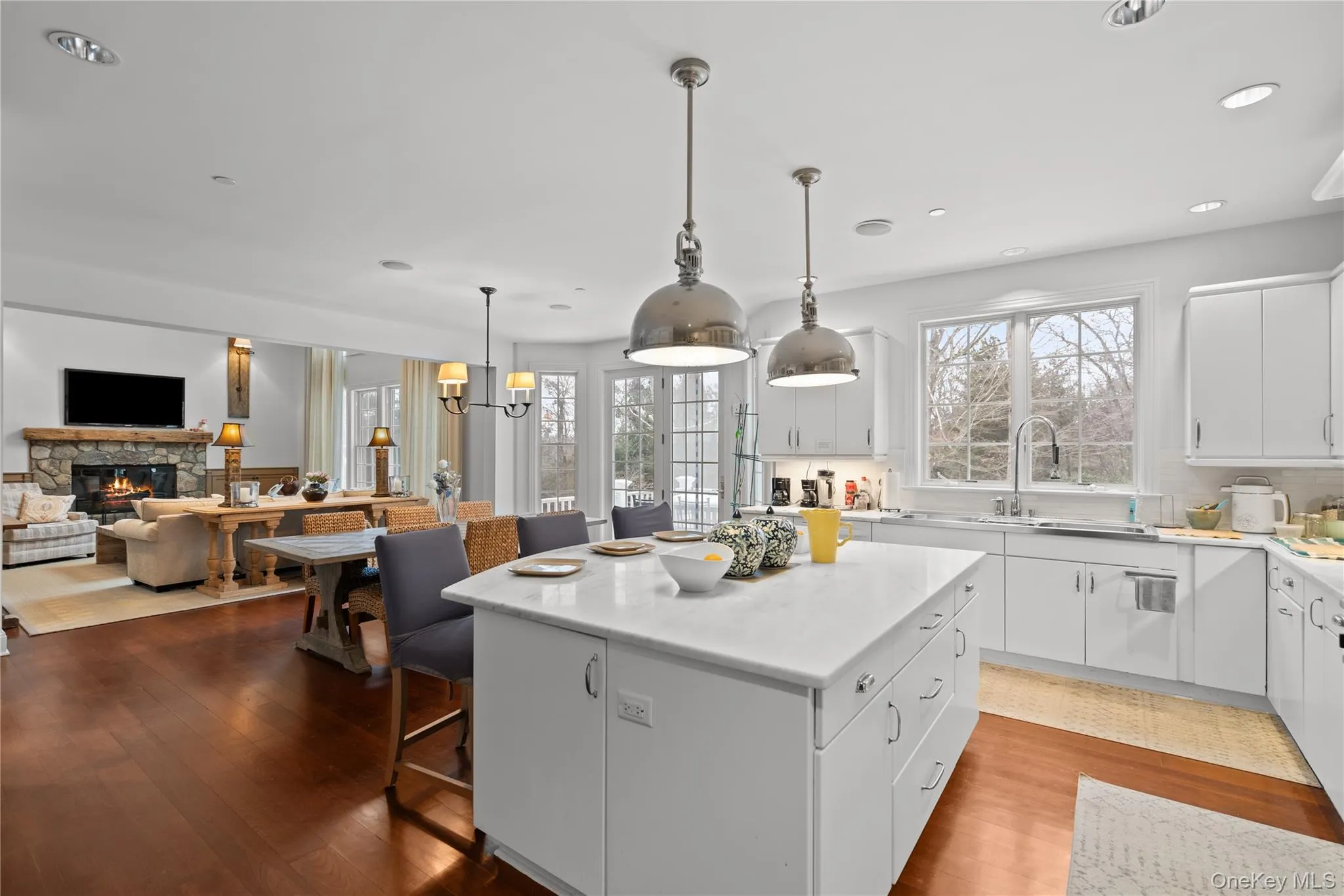 Kitchen with white cabinetry, a kitchen breakfast bar, open floor plan, a stone fireplace, and a center island Kitchen with white cabinetry, a kitchen breakfast bar, open floor plan, a stone fireplace, and a center island