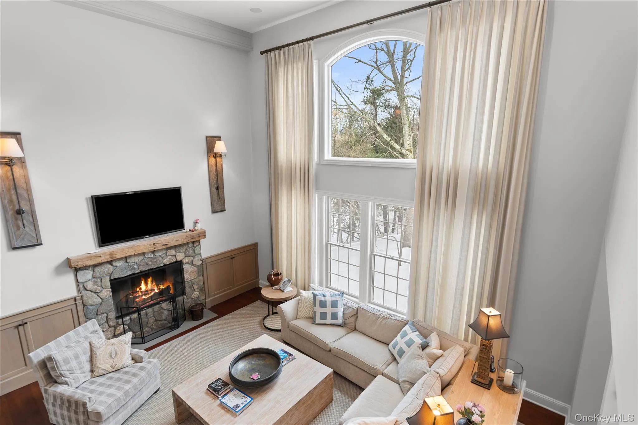 Living room featuring ornamental molding, a fireplace, wood finished floors, and wainscoting Living room featuring ornamental molding, a fireplace, wood finished floors, and wainscoting