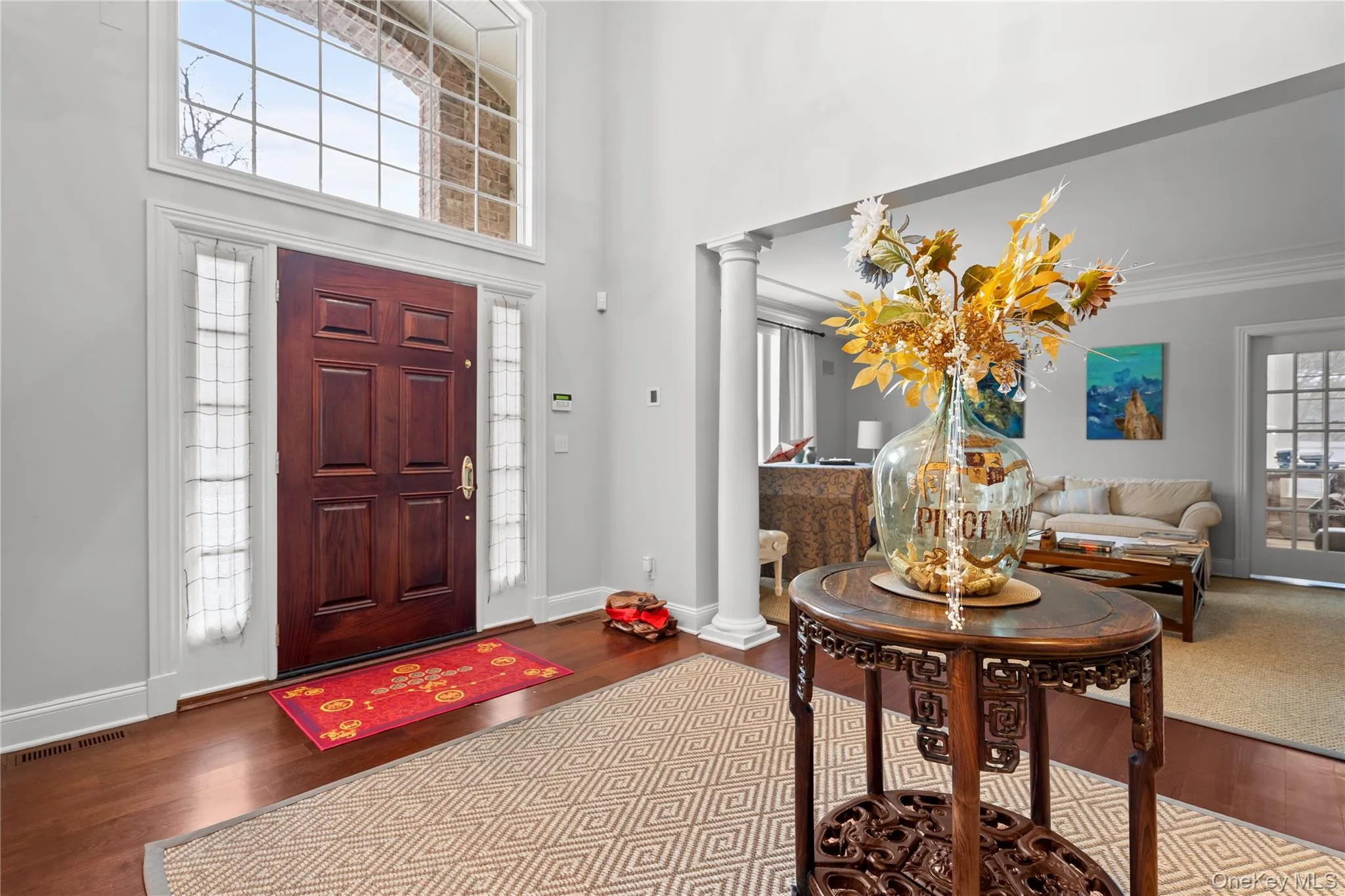 Foyer entrance with decorative columns, dark wood-style flooring, and a high ceiling Foyer entrance with decorative columns, dark wood-style flooring, and a high ceiling