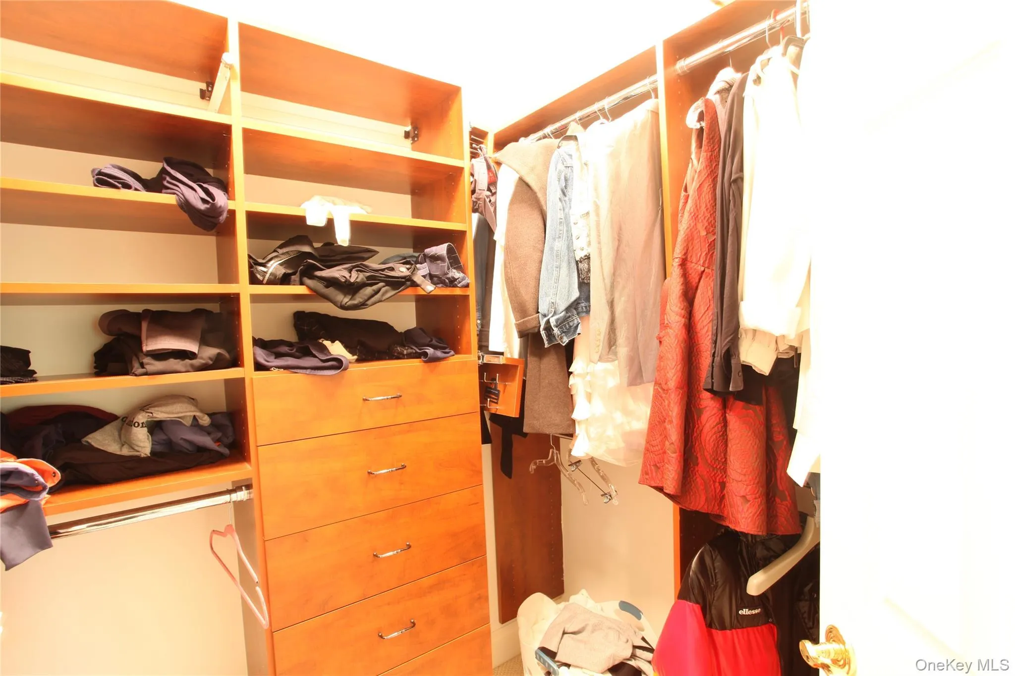 Custom closet system featuring wood-finish shelving, multiple hanging rods, and integrated dresser drawers with chrome hardware Custom closet system featuring wood-finish shelving, multiple hanging rods, and integrated dresser drawers with chrome hardware