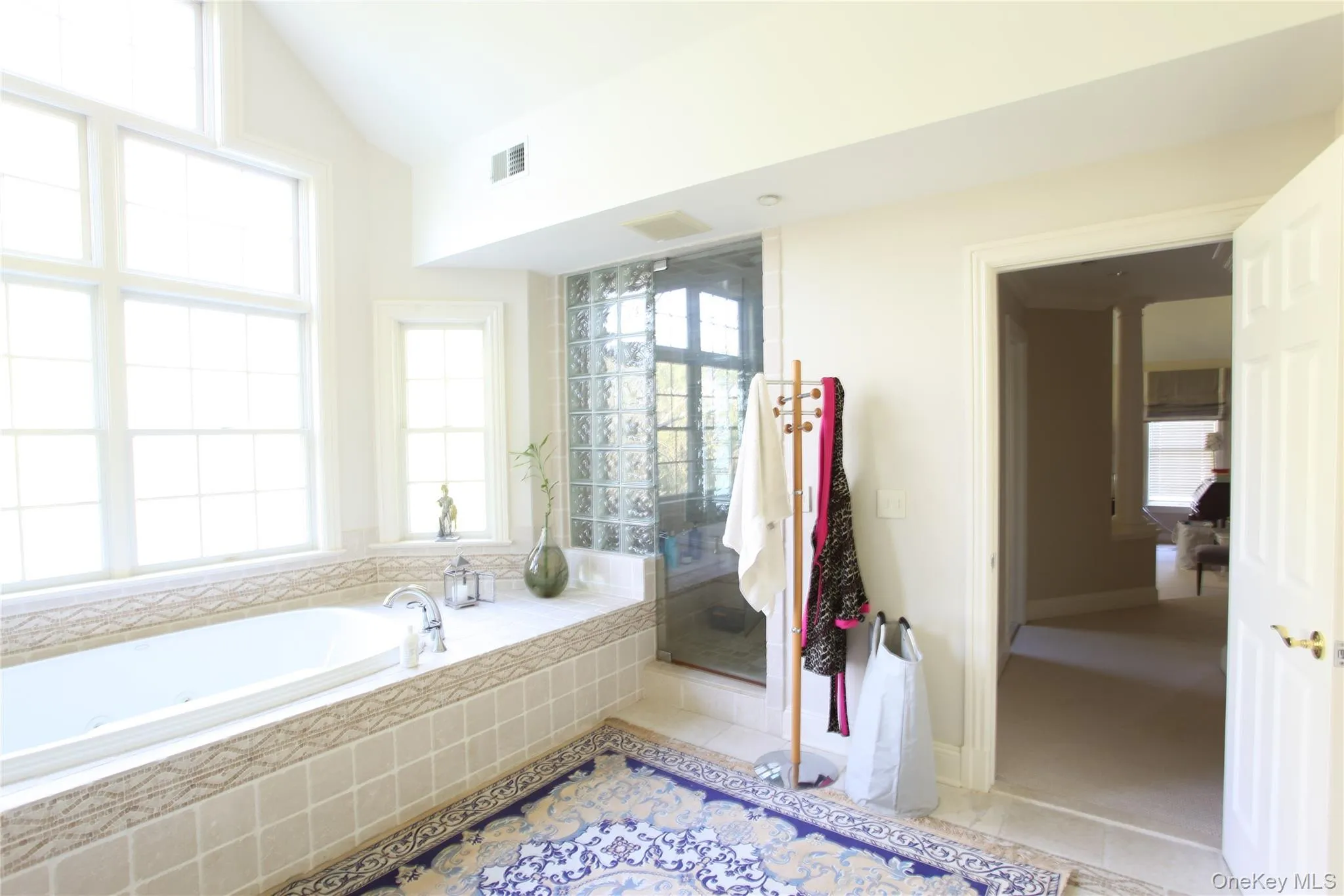 Soaking tub with tiled surround, large grid-patterned windows, and glass block shower enclosure Soaking tub with tiled surround, large grid-patterned windows, and glass block shower enclosure