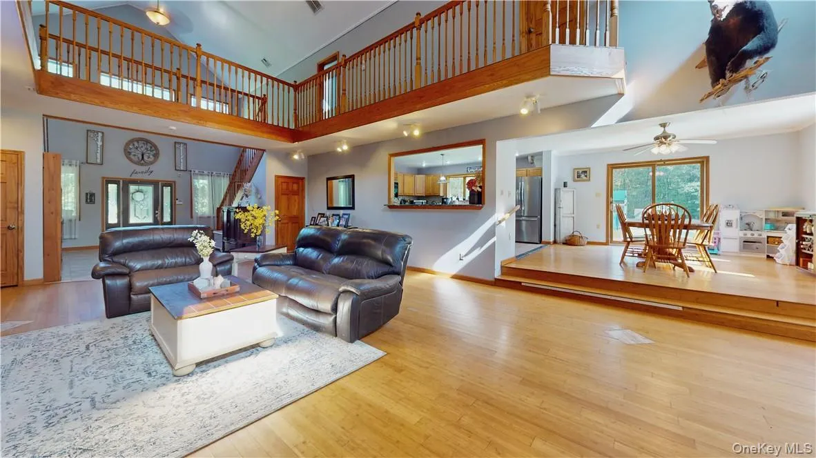 Living room featuring light hardwood / wood-style flooring, a high ceiling, and ceiling fan Living room featuring light hardwood / wood-style flooring, a high ceiling, and ceiling fan