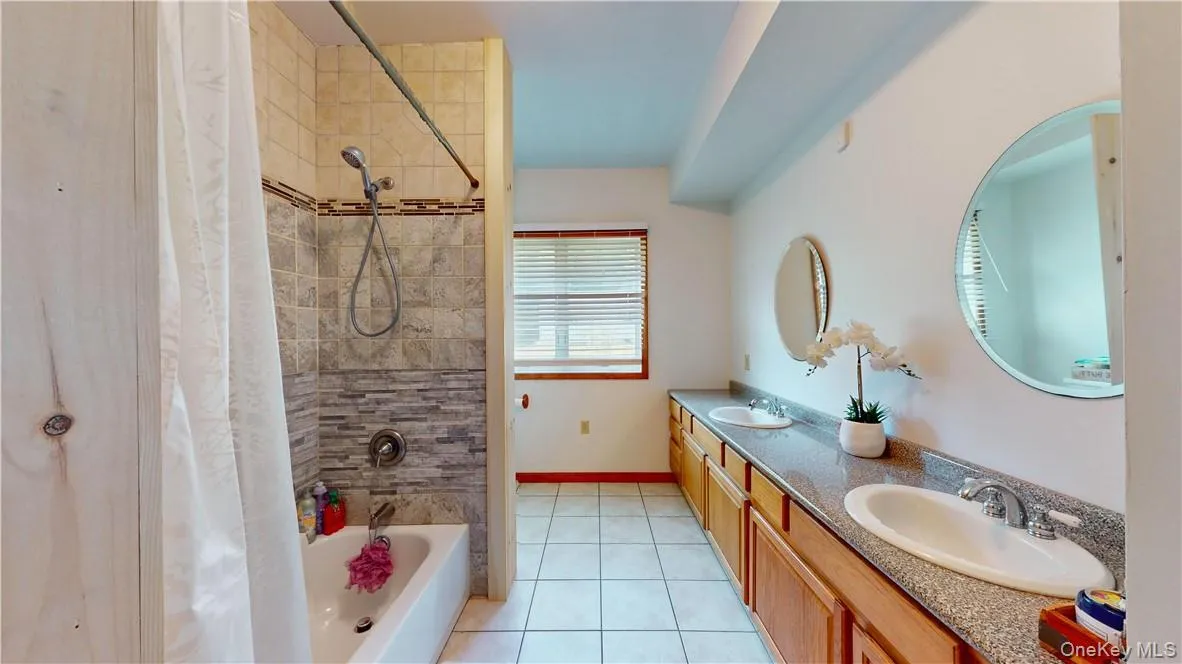 Bathroom featuring tile patterned flooring, vanity, and shower / bath combination with curtain Bathroom featuring tile patterned flooring, vanity, and shower / bath combination with curtain
