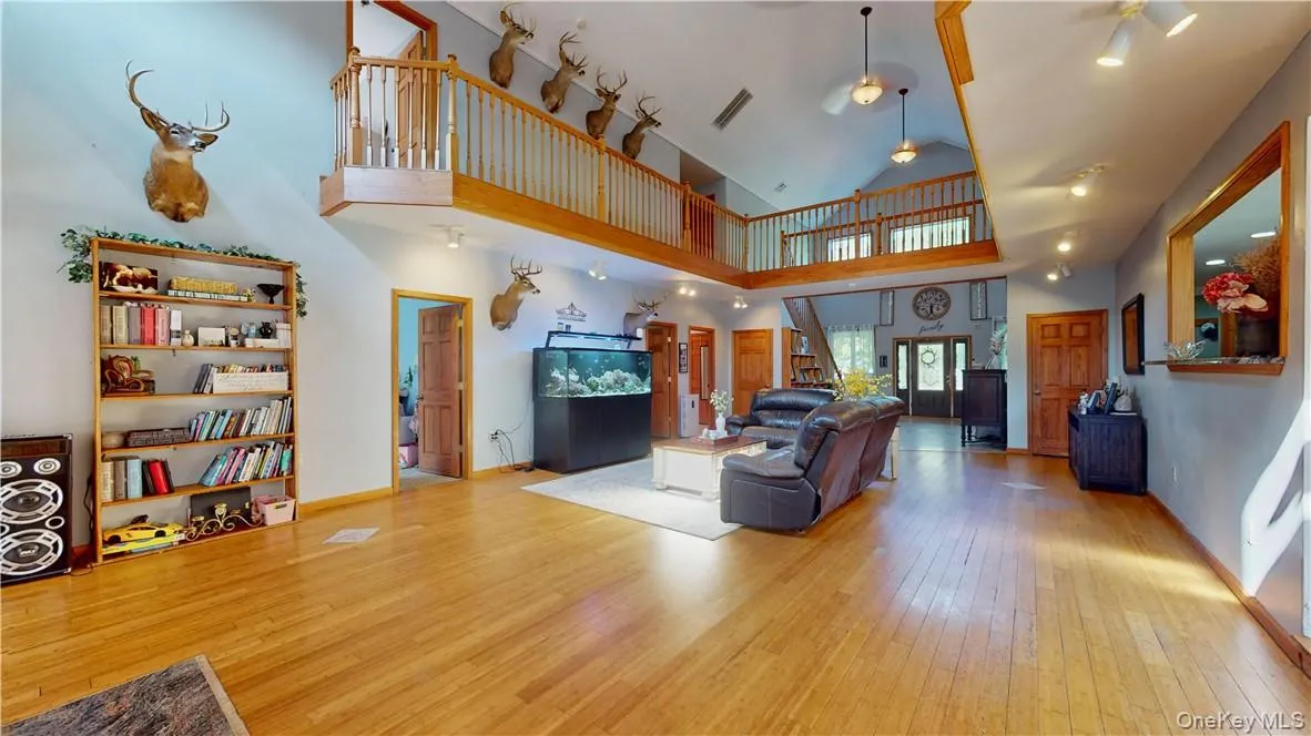 Living room featuring light wood-type flooring and high vaulted ceiling Living room featuring light wood-type flooring and high vaulted ceiling