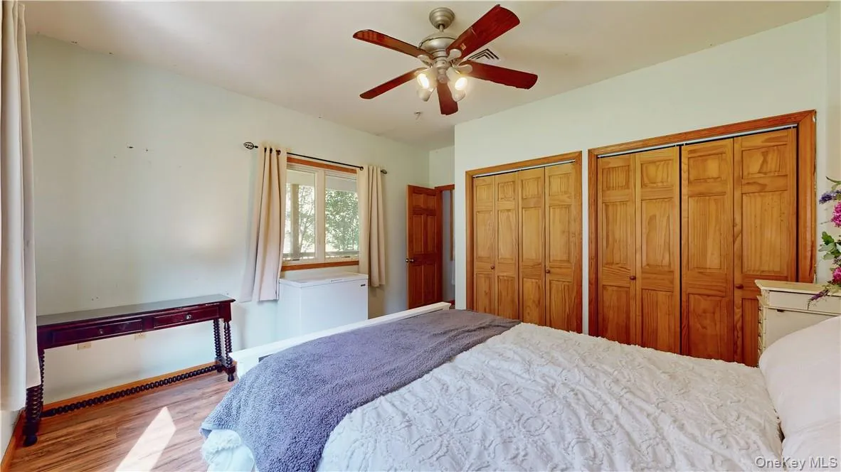 Bedroom featuring light hardwood / wood-style flooring, ceiling fan, and multiple closets Bedroom featuring light hardwood / wood-style flooring, ceiling fan, and multiple closets