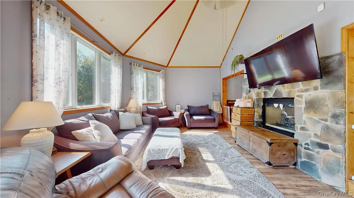 Living room with light wood-type flooring, high vaulted ceiling, a fireplace, and crown molding Living room with light wood-type flooring, high vaulted ceiling, a fireplace, and crown molding