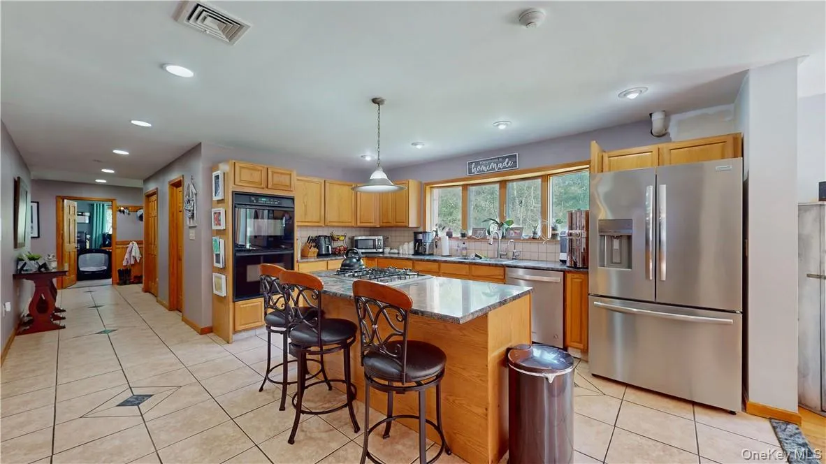Kitchen featuring decorative light fixtures, sink, a center island, light stone countertops, and appliances with stainless steel finishes Kitchen featuring decorative light fixtures, sink, a center island, light stone countertops, and appliances with stainless steel finishes