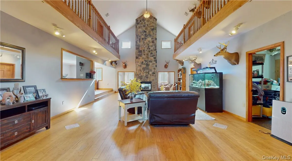 Living room with light hardwood / wood-style flooring, a stone fireplace, and high vaulted ceiling Living room with light hardwood / wood-style flooring, a stone fireplace, and high vaulted ceiling