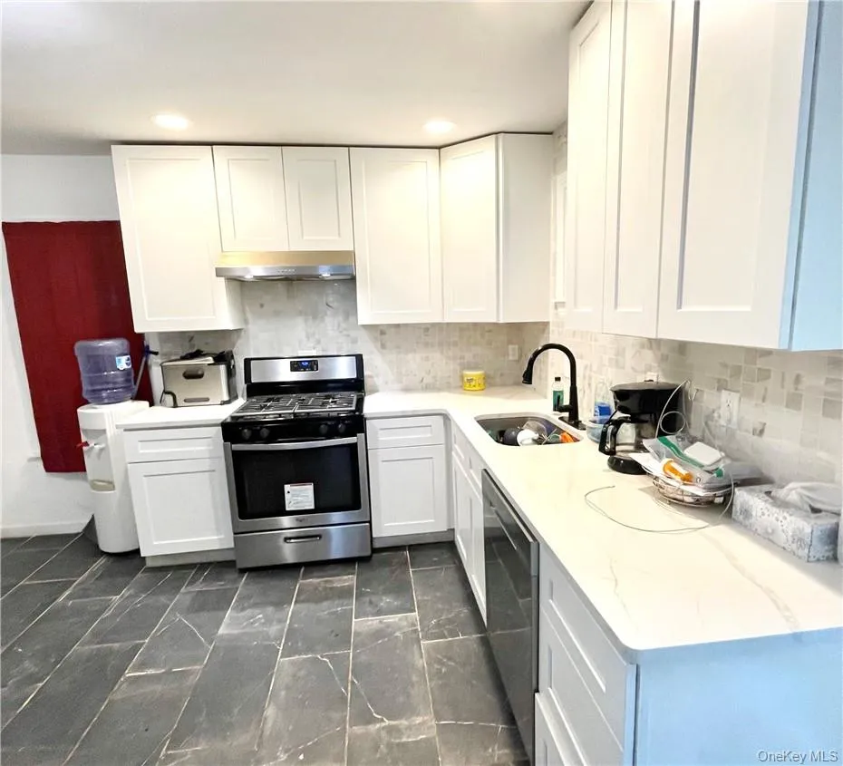 Kitchen with white cabinets, backsplash, dishwasher, stainless steel gas stove, and sink Kitchen with white cabinets, backsplash, dishwasher, stainless steel gas stove, and sink
