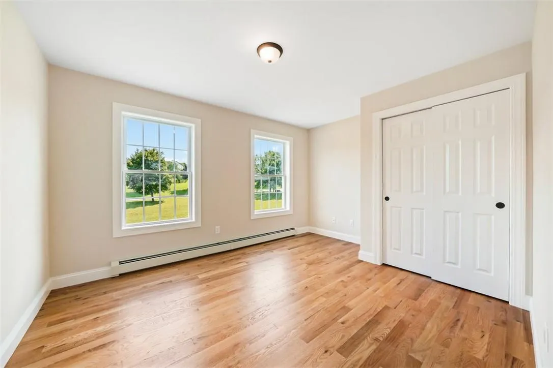 Unfurnished bedroom with light wood-type flooring, a closet, and a baseboard heating unit Unfurnished bedroom with light wood-type flooring, a closet, and a baseboard heating unit