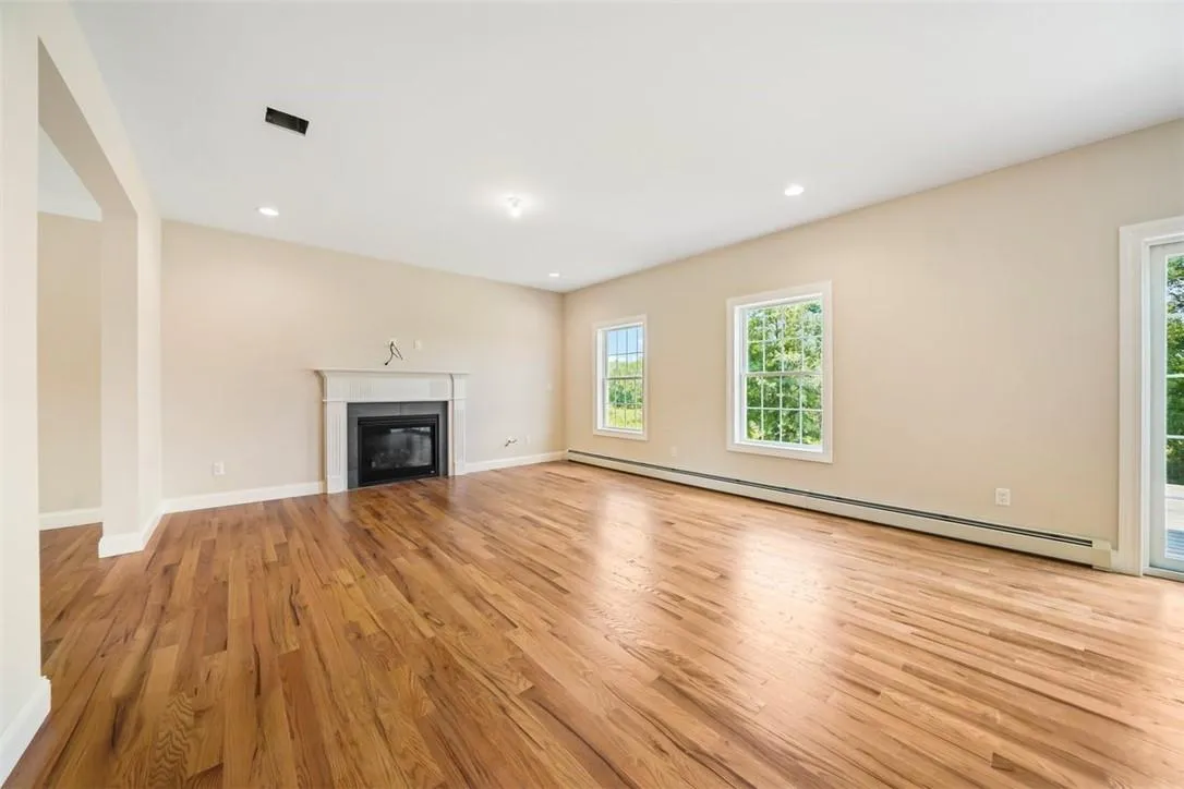 Unfurnished living room featuring light hardwood / wood-style flooring and baseboard heating Unfurnished living room featuring light hardwood / wood-style flooring and baseboard heating
