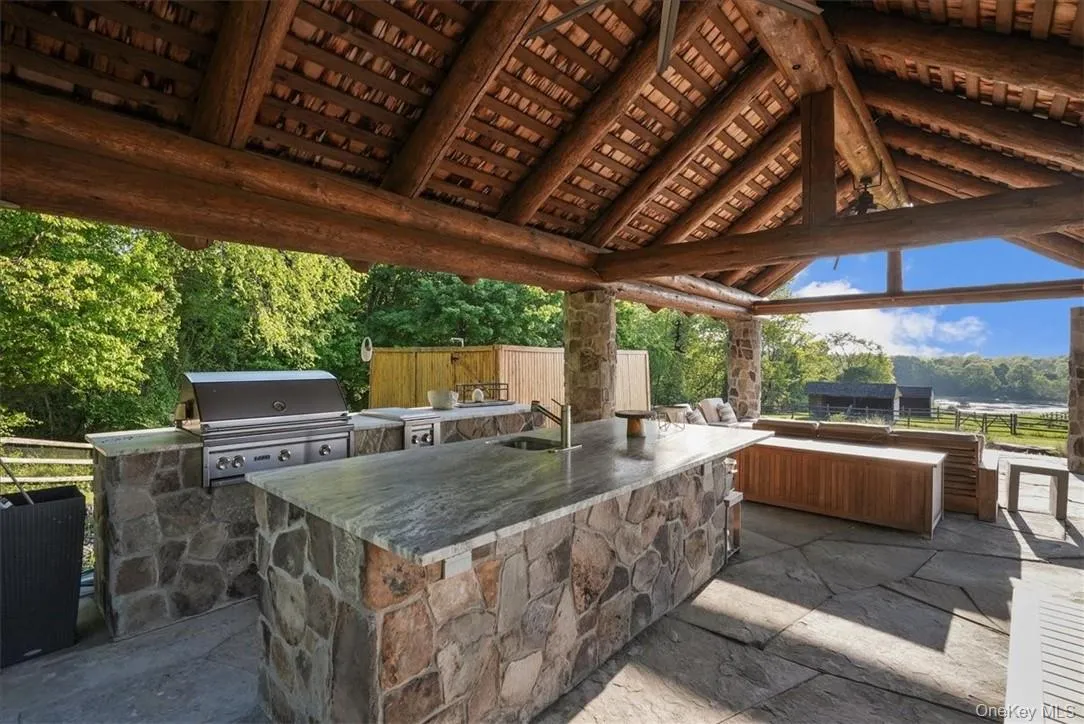 Custom outdoor kitchen pavilion with hot and cold water, Lynx appliances, refrigerator, storage and beautiful seating areas. An outdoor shower is located beyond the pavilion. Custom outdoor kitchen pavilion with hot and cold water, Lynx appliances, refrigerator, storage and beautiful seating areas. An outdoor shower is located beyond the pavilion.