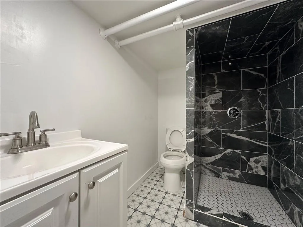 Bathroom featuring vanity, toilet, a tile shower, and tile patterned flooring Bathroom featuring vanity, toilet, a tile shower, and tile patterned flooring
