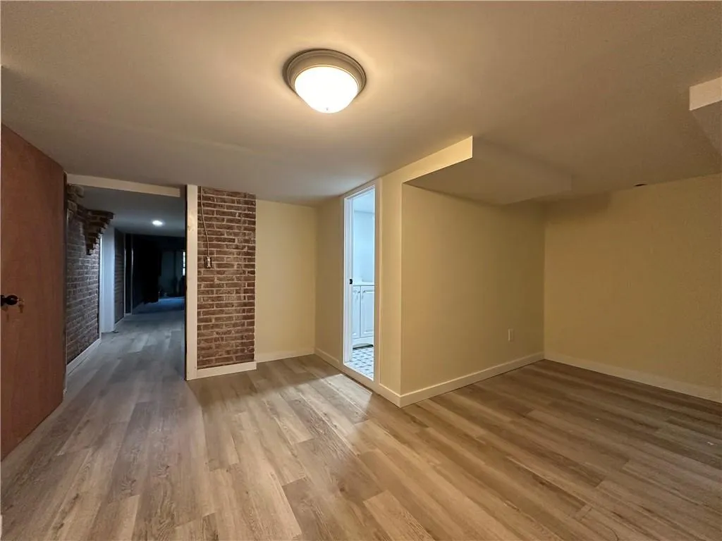 Spare room featuring hardwood / wood-style flooring and brick wall Spare room featuring hardwood / wood-style flooring and brick wall