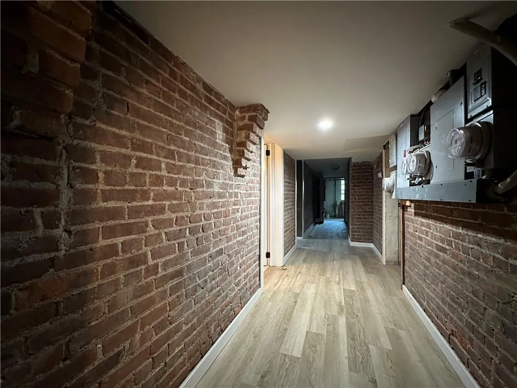 Hall with hardwood / wood-style flooring and brick wall Hall with hardwood / wood-style flooring and brick wall