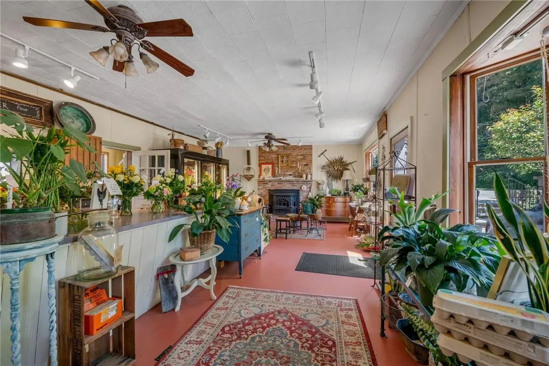 Sunroom / solarium featuring a brick fireplace, ceiling fan, and track lighting Sunroom / solarium featuring a brick fireplace, ceiling fan, and track lighting