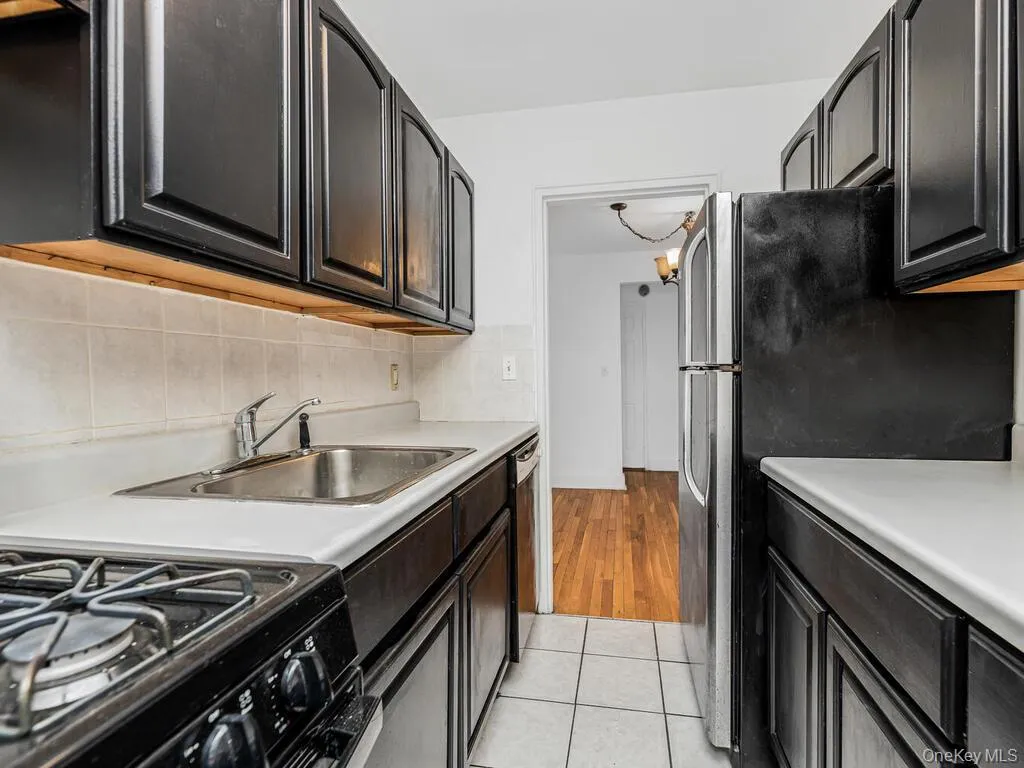 Kitchen featuring light tile patterned flooring, appliances with stainless steel finishes, sink, and tasteful backsplash Kitchen featuring light tile patterned flooring, appliances with stainless steel finishes, sink, and tasteful backsplash