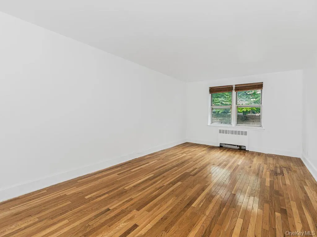 Empty room with hardwood / wood-style flooring and radiator heating unit Empty room with hardwood / wood-style flooring and radiator heating unit