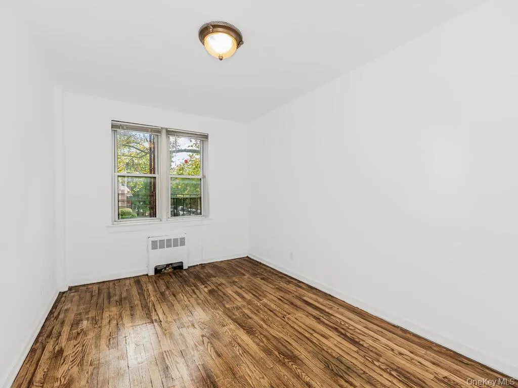 Spare room featuring hardwood / wood-style floors and radiator heating unit Spare room featuring hardwood / wood-style floors and radiator heating unit