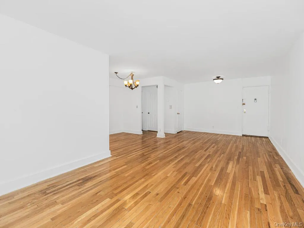 Unfurnished living room with an inviting chandelier and light wood-type flooring Unfurnished living room with an inviting chandelier and light wood-type flooring