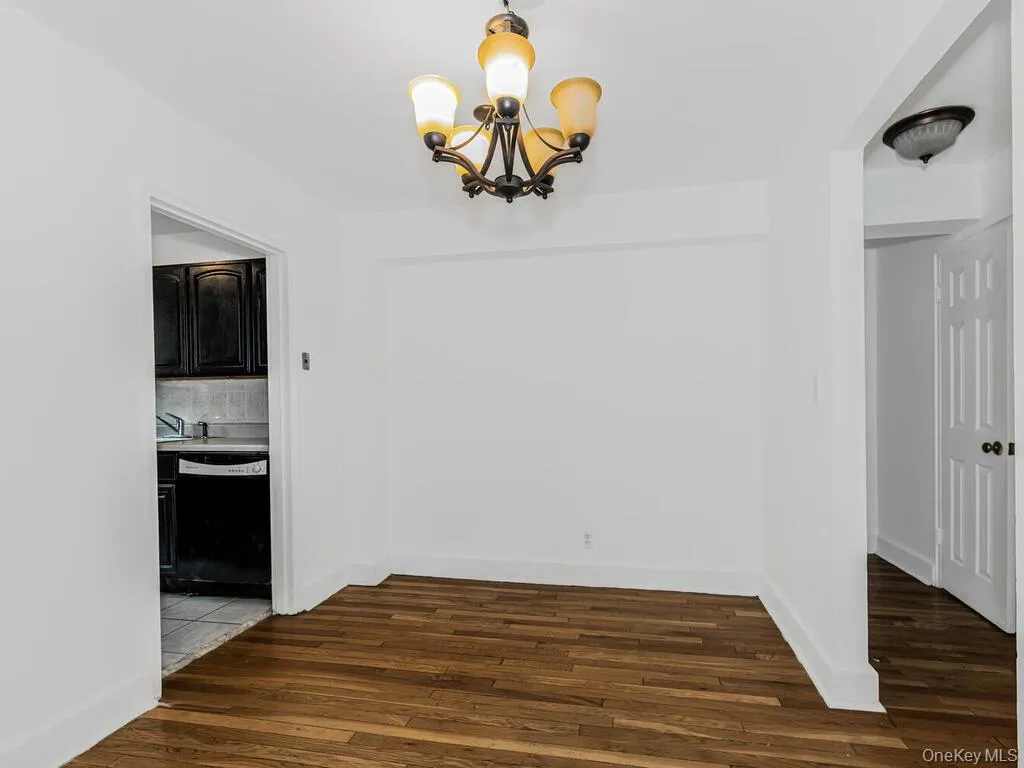 Unfurnished dining area with a chandelier and dark wood-type flooring Unfurnished dining area with a chandelier and dark wood-type flooring