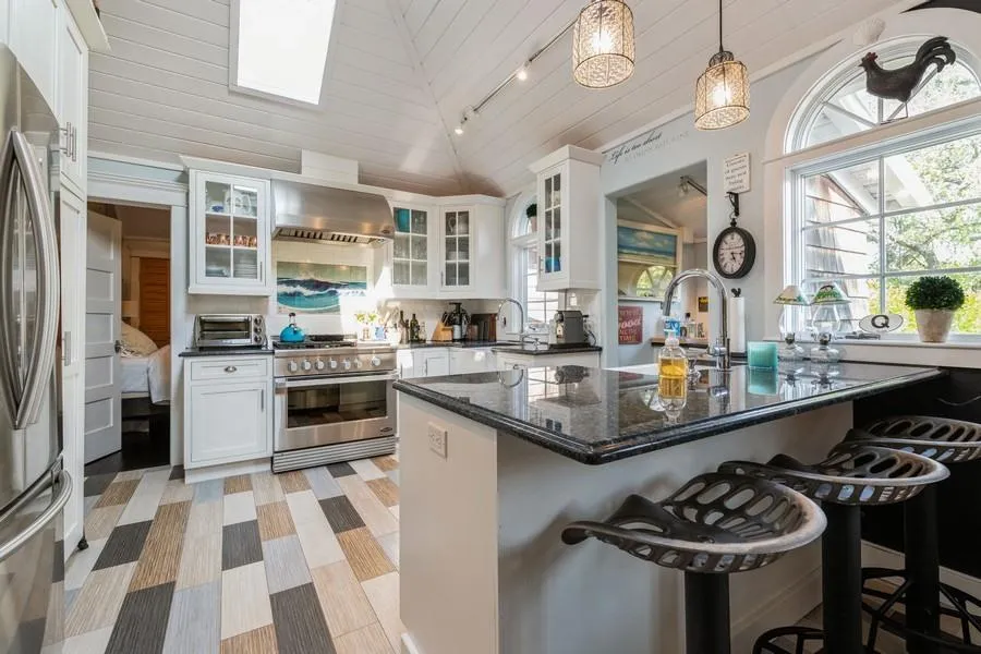 Kitchen with stainless steel appliances, lofted ceiling, a kitchen bar, and white cabinets Kitchen with stainless steel appliances, lofted ceiling, a kitchen bar, and white cabinets