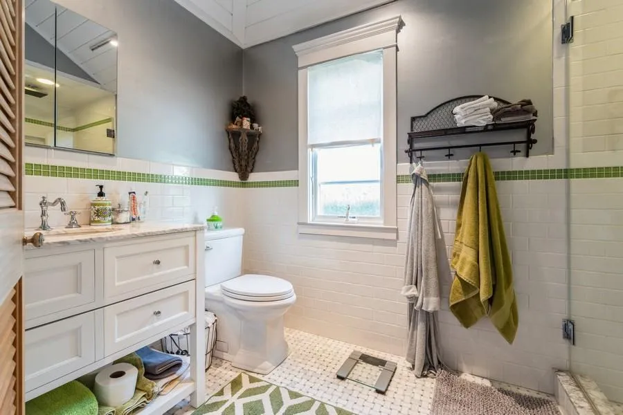 Bathroom featuring tile patterned floors, toilet, a shower with shower door, vanity, and tile walls Bathroom featuring tile patterned floors, toilet, a shower with shower door, vanity, and tile walls