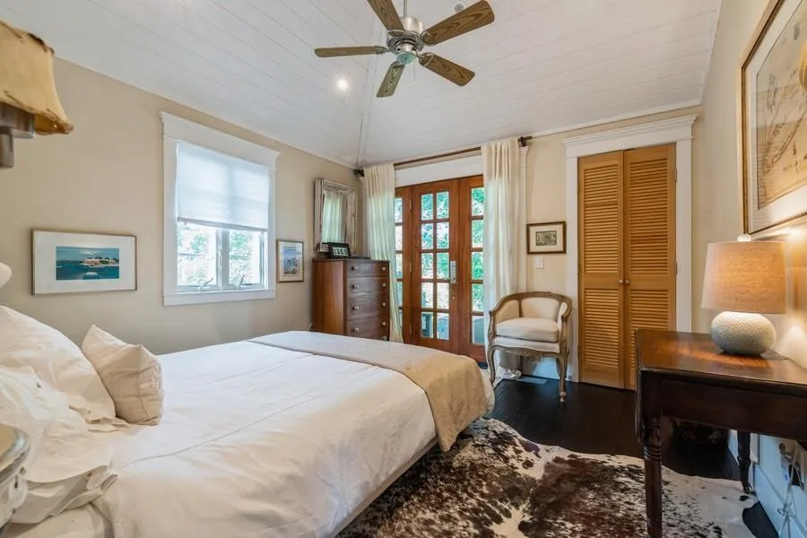 Bedroom featuring multiple windows, french doors, dark wood-type flooring, and ceiling fan Bedroom featuring multiple windows, french doors, dark wood-type flooring, and ceiling fan