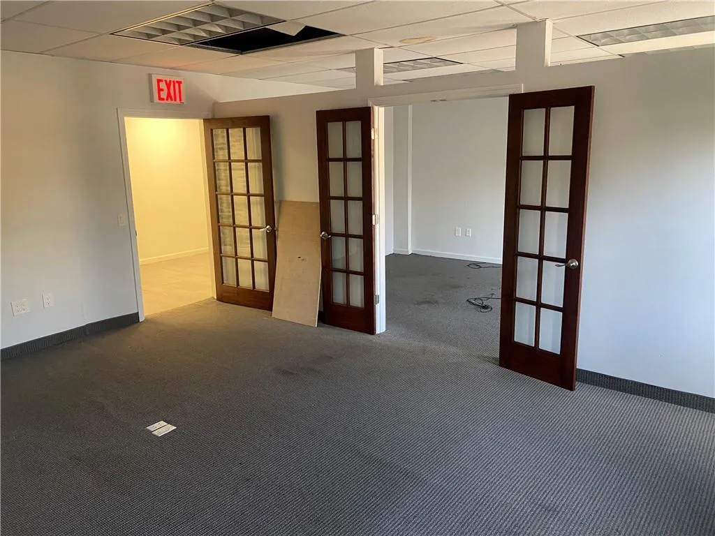 Spare room featuring french doors, carpet floors, and a drop ceiling Spare room featuring french doors, carpet floors, and a drop ceiling