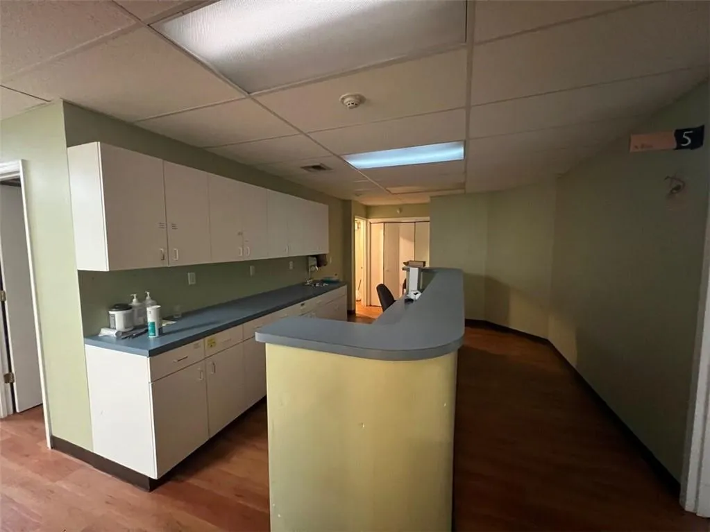 Kitchen with light hardwood / wood-style floors, kitchen peninsula, a paneled ceiling, and white cabinets Kitchen with light hardwood / wood-style floors, kitchen peninsula, a paneled ceiling, and white cabinets