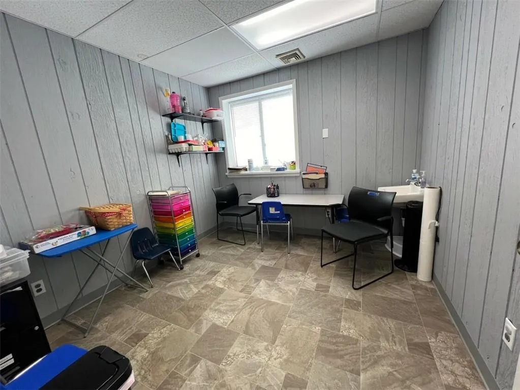 Living area featuring a drop ceiling and wood walls Living area featuring a drop ceiling and wood walls