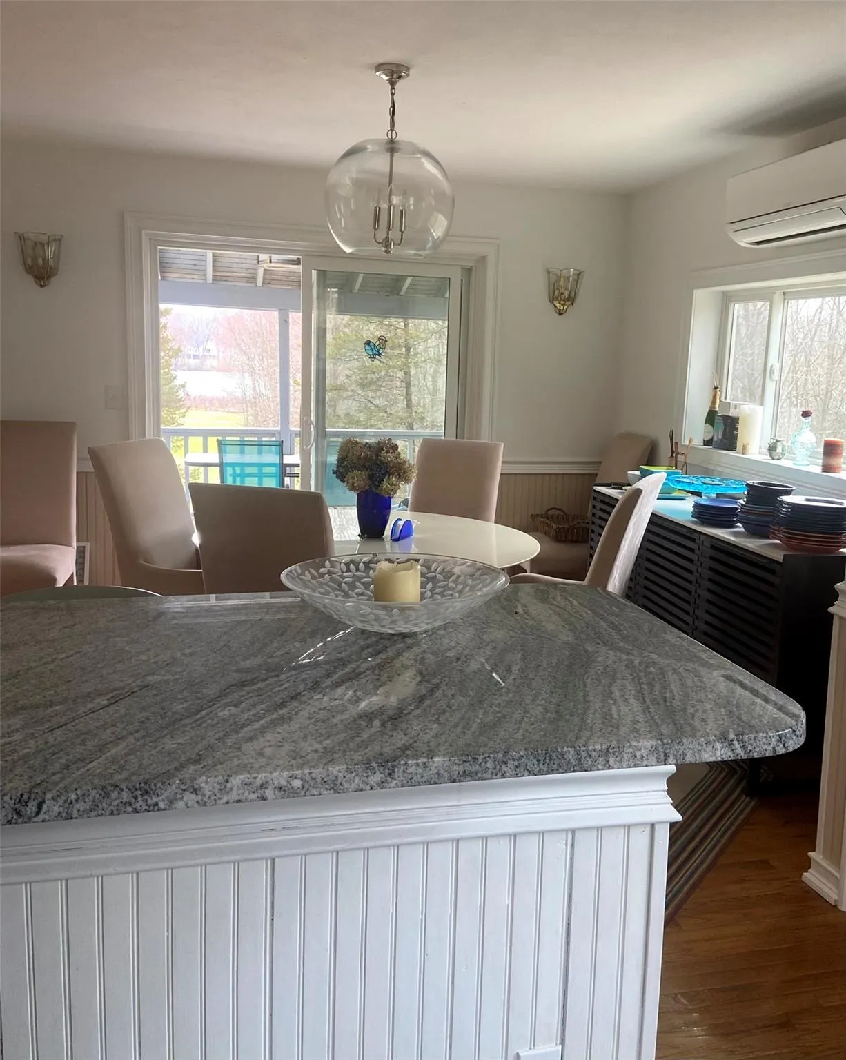 Dining room featuring wood finished floors, a wall mounted air conditioner, a chandelier, and wainscoting Dining room featuring wood finished floors, a wall mounted air conditioner, a chandelier, and wainscoting