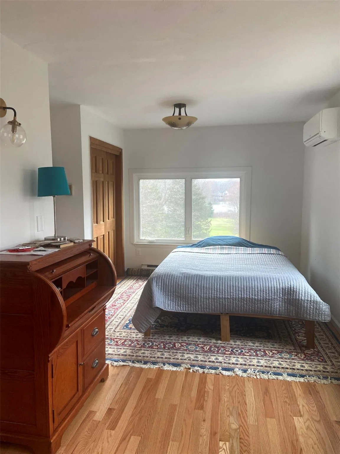 Bedroom featuring a wall mounted AC and light wood-type flooring Bedroom featuring a wall mounted AC and light wood-type flooring